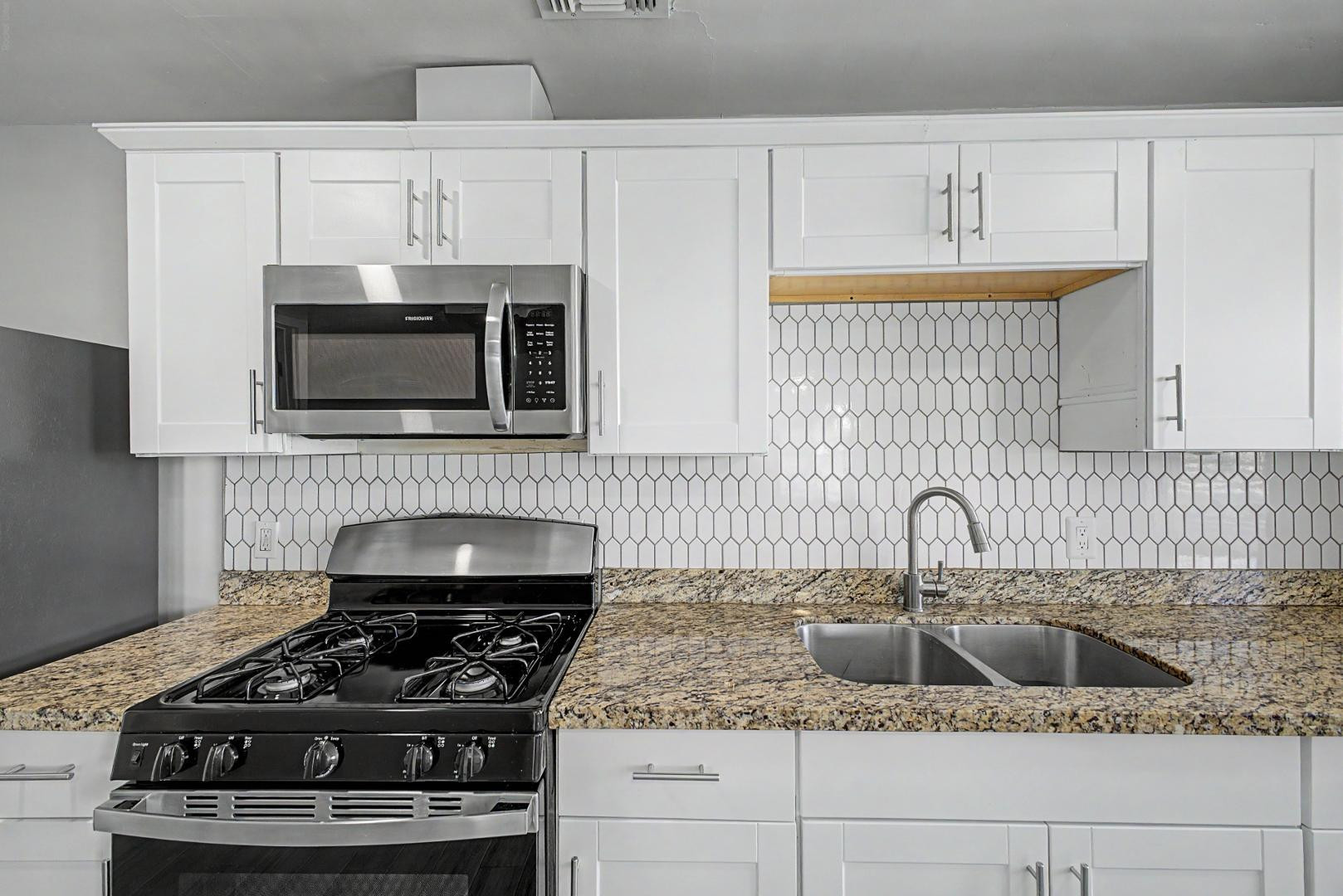 2534 North 28th Street Phoenix, AZ 85008 - Photo 15 of 33 a kitchen with white cabinets a sink and a stove