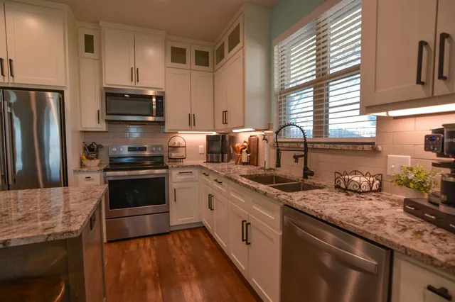 a kitchen with stainless steel appliances granite countertop a sink stove microwave refrigerator and cabinets