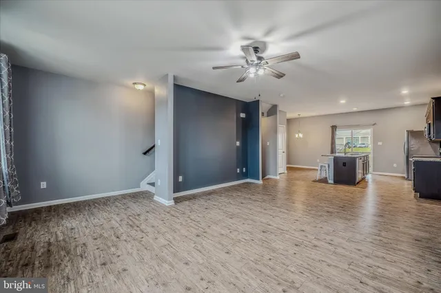 an empty room with wooden floor chandelier fan and windows