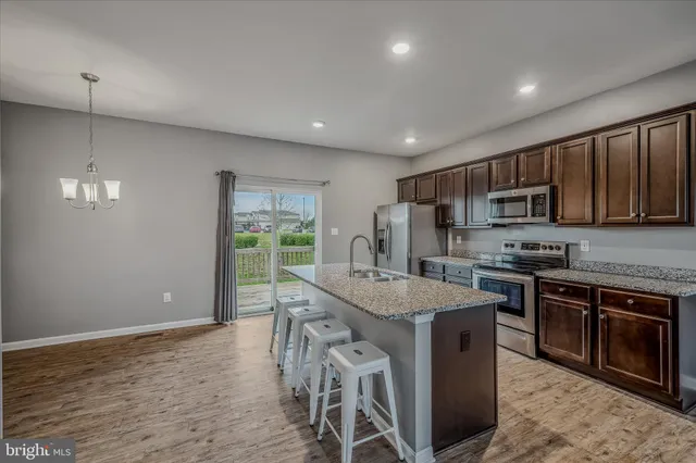 a kitchen with stainless steel appliances granite countertop a stove a refrigerator a sink a microwave and island