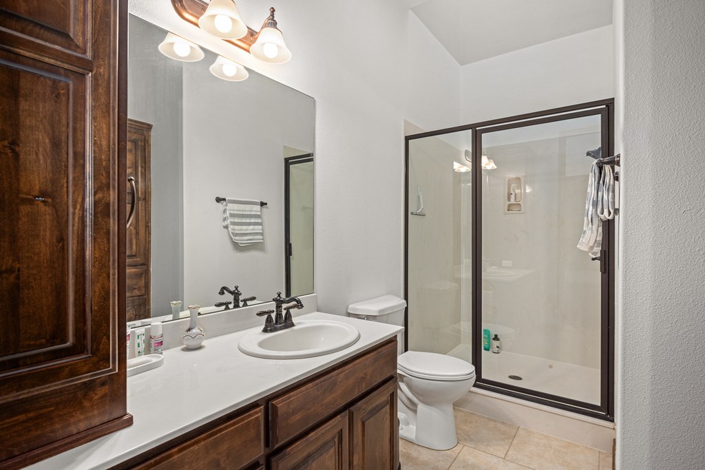 3801-12 Club House Road Kerrville, TX 78028 - Photo 11 of 23 a bathroom with a granite countertop sink toilet a large mirror a glass door and shower