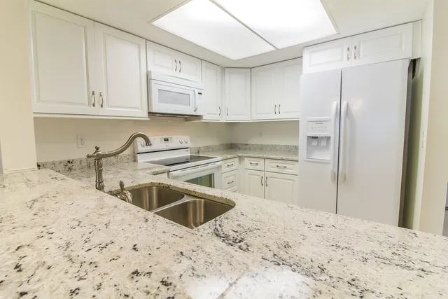 a kitchen with granite countertop a sink stove and refrigerator