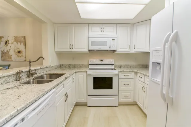 a kitchen with granite countertop white cabinets and white appliances