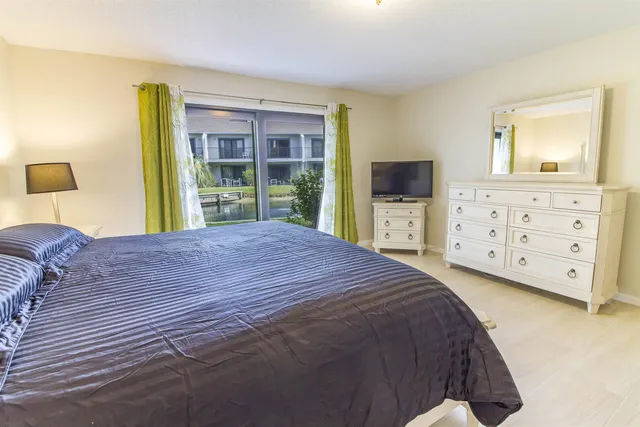 a bedroom with a bed and a flat tv screen on dresser