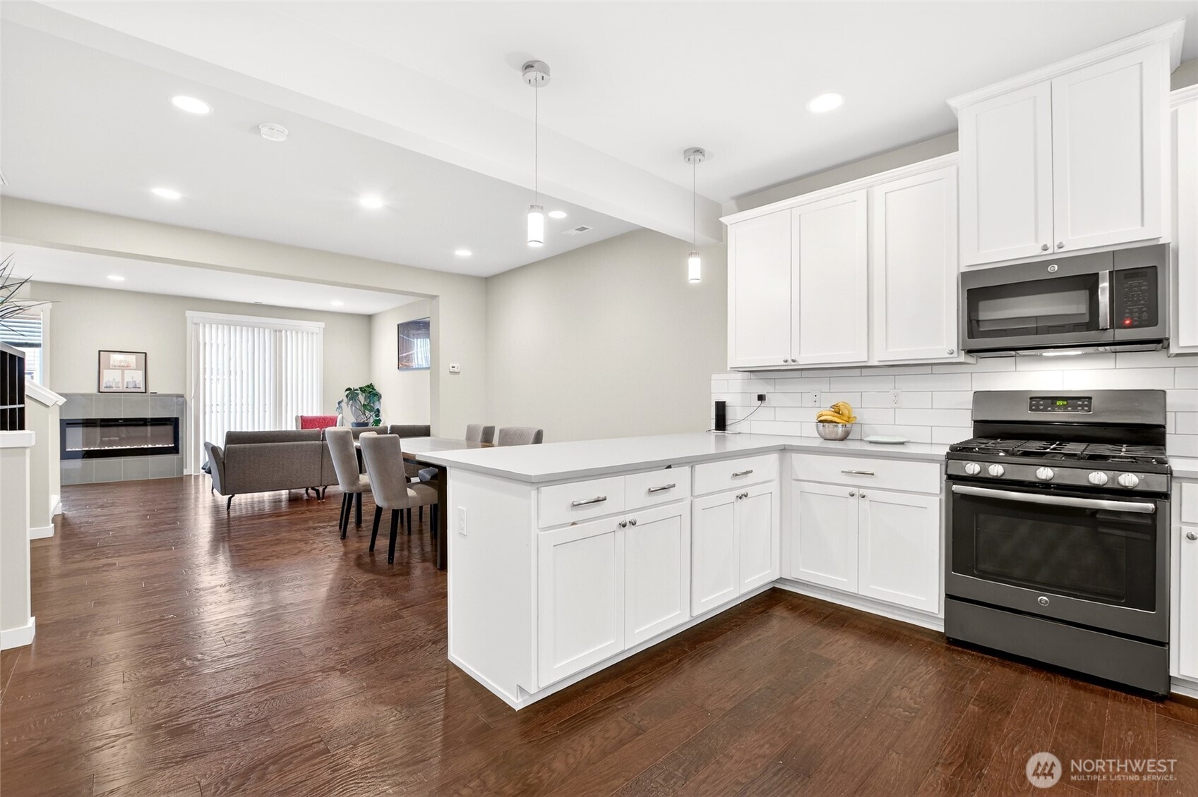 22925 79th Place West, Unit B Edmonds, WA 98026 - Photo 8 of 39 a kitchen with stainless steel appliances kitchen island granite countertop a stove top oven a sink a dining table and chairs with wooden floor