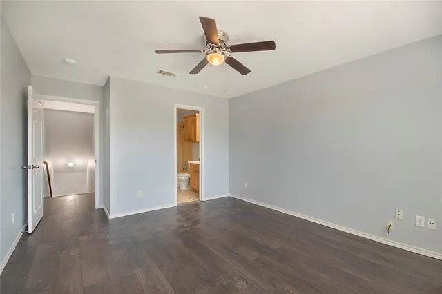 a view of an empty room with wooden floor and a ceiling fan