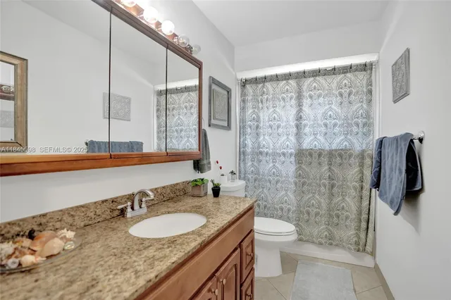 a bathroom with a granite countertop sink a toilet a mirror and shower
