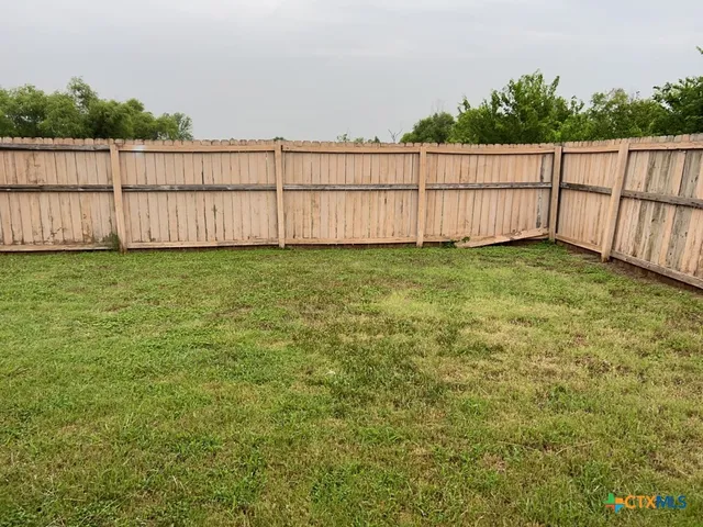 a view of a backyard with wooden fence