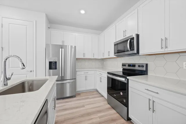 a kitchen with stainless steel appliances granite countertop a refrigerator sink and white cabinets