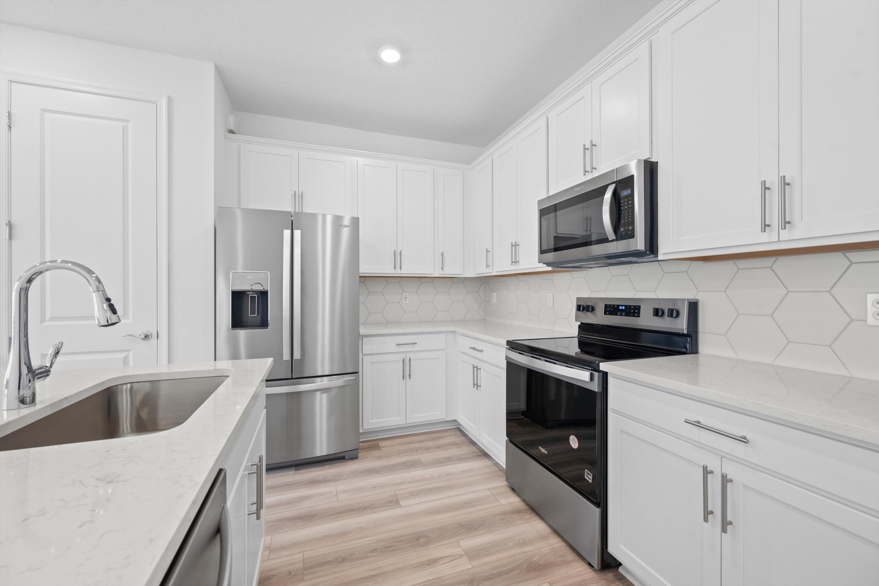 7638 Southwest Lucy Lane Stuart, FL 34997 - Photo 13 of 45 a kitchen with stainless steel appliances granite countertop a refrigerator sink and white cabinets