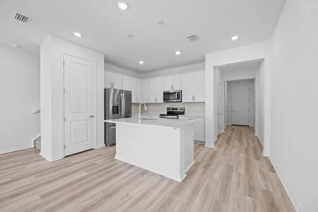 a kitchen with stainless steel appliances granite countertop a refrigerator oven a sink dishwasher and white cabinets with wooden floor