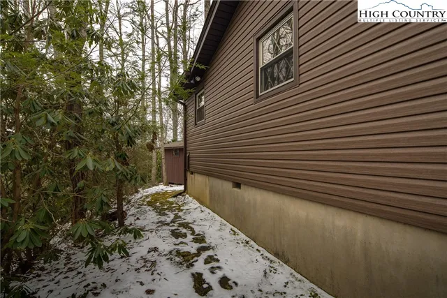 a backyard of a house with large trees and wooden fence