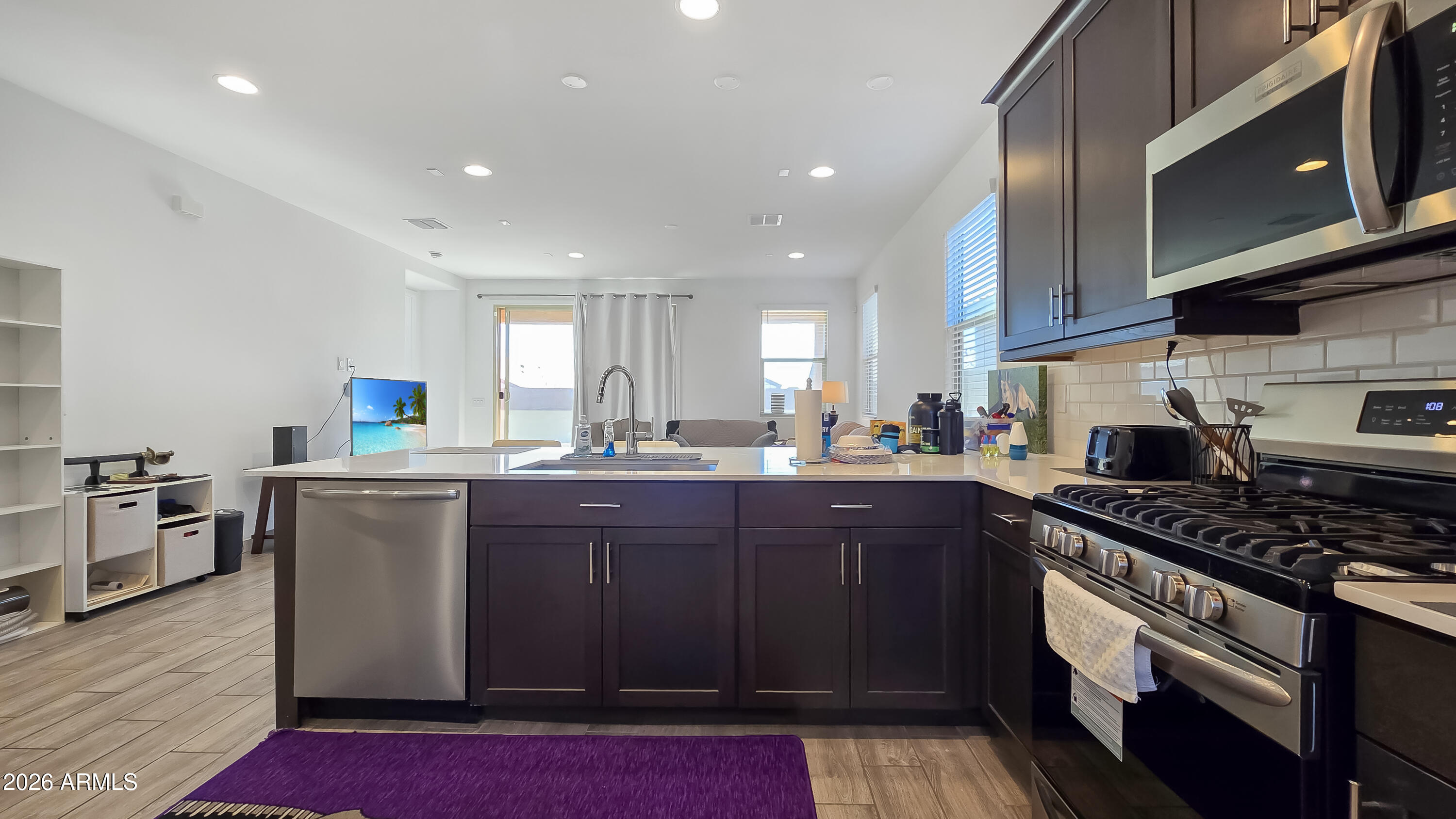 16839 West Evergreen Road Waddell, AZ 85355 - Photo 8 of 28 a kitchen with stainless steel appliances granite countertop a stove a sink dishwasher and a microwave oven with large wooden cabinets