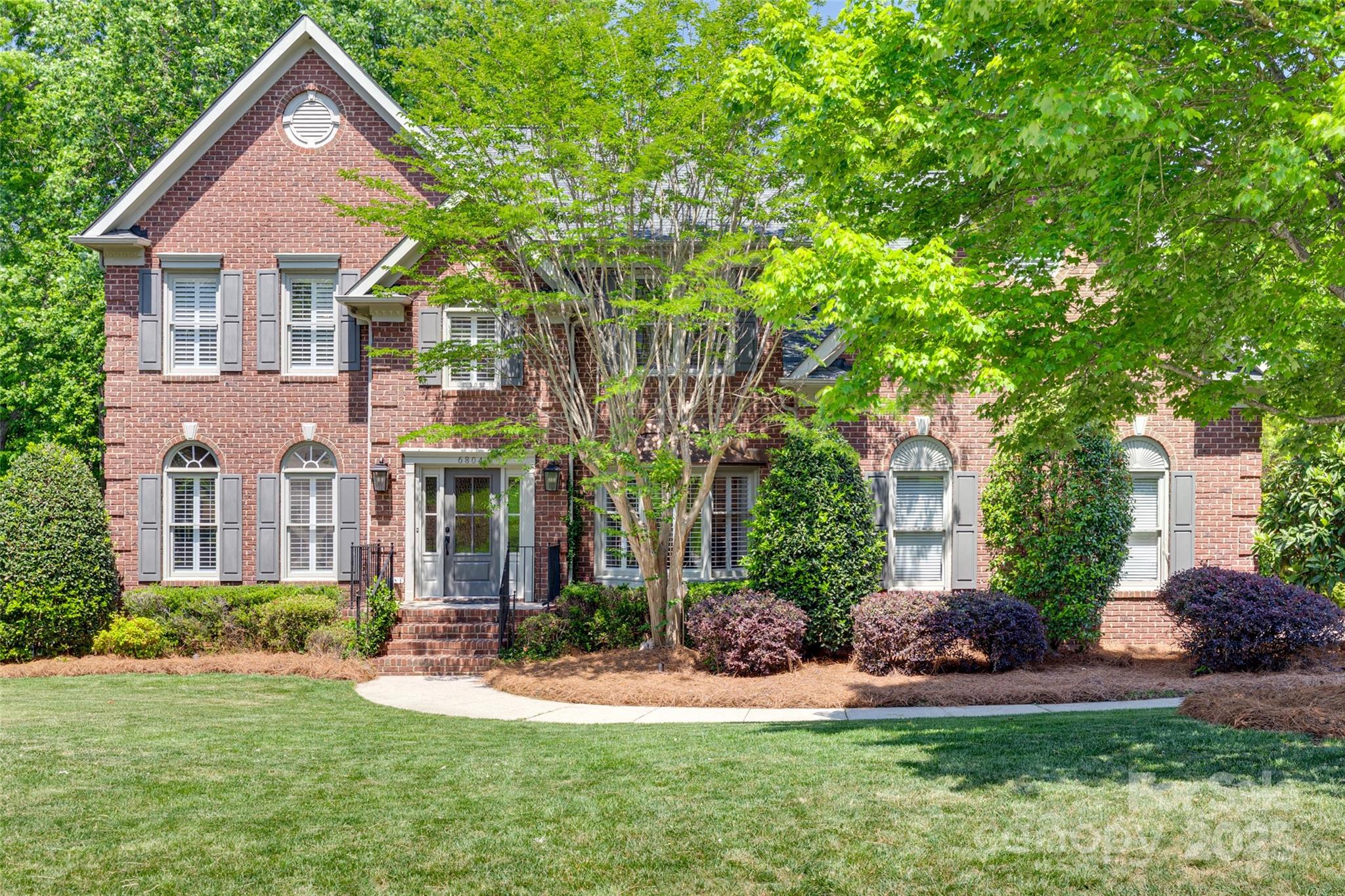 a front view of a house with a yard and trees