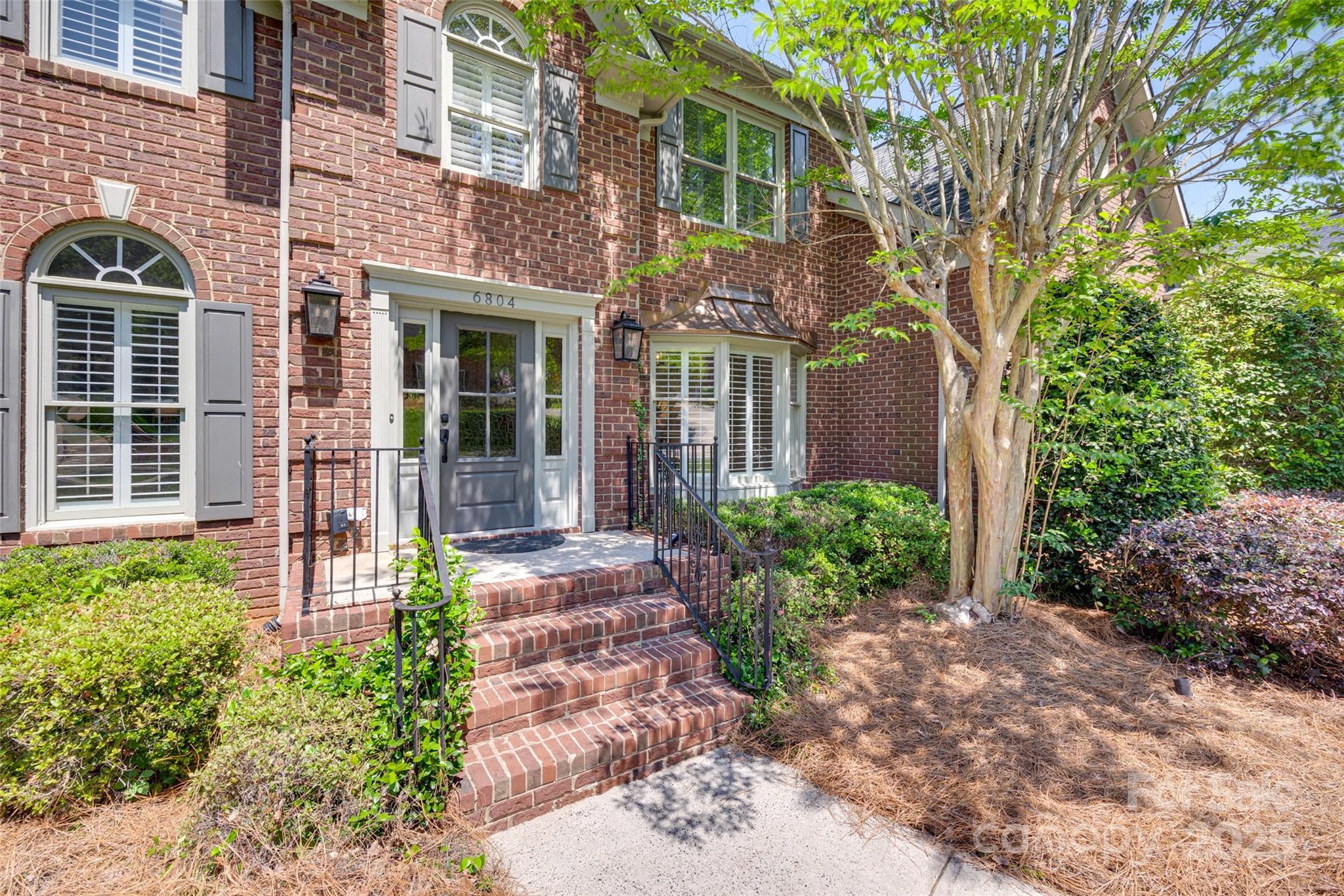6804 Riesman Lane Charlotte, NC 28210 - Photo 2 of 46 a front view of a brick house with a large windows and flower plants