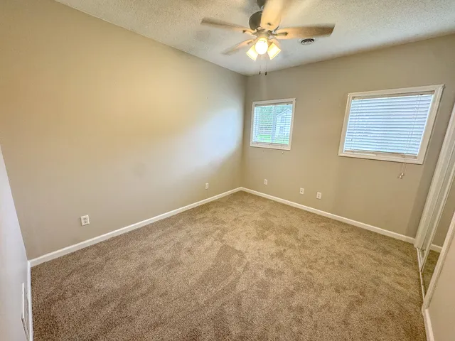a view of an empty room and chandelier fan