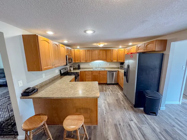 a kitchen with a table chairs refrigerator and wooden floor