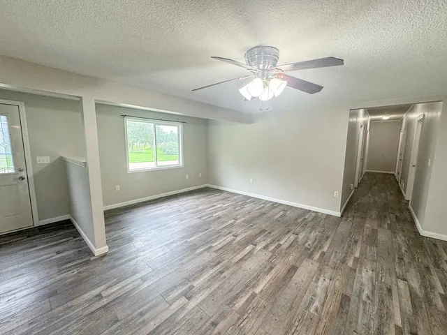 a view of an empty room with wooden floor and a window