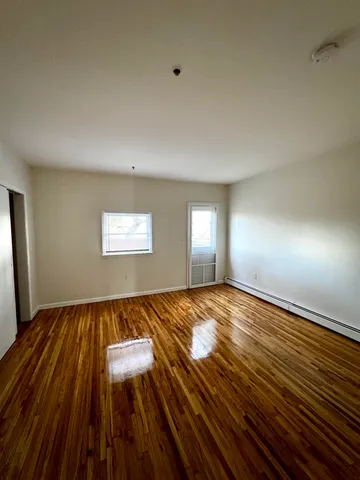 a view of an empty room with wooden floor and window