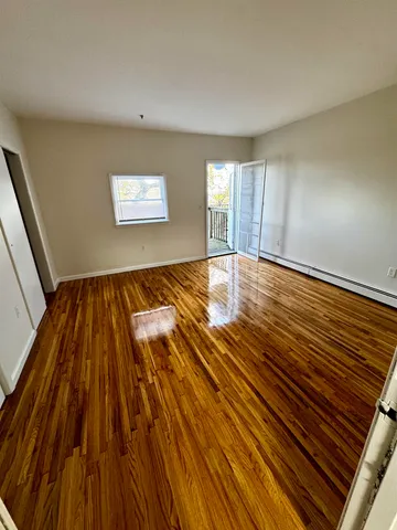 a view of an empty room with wooden floor and window