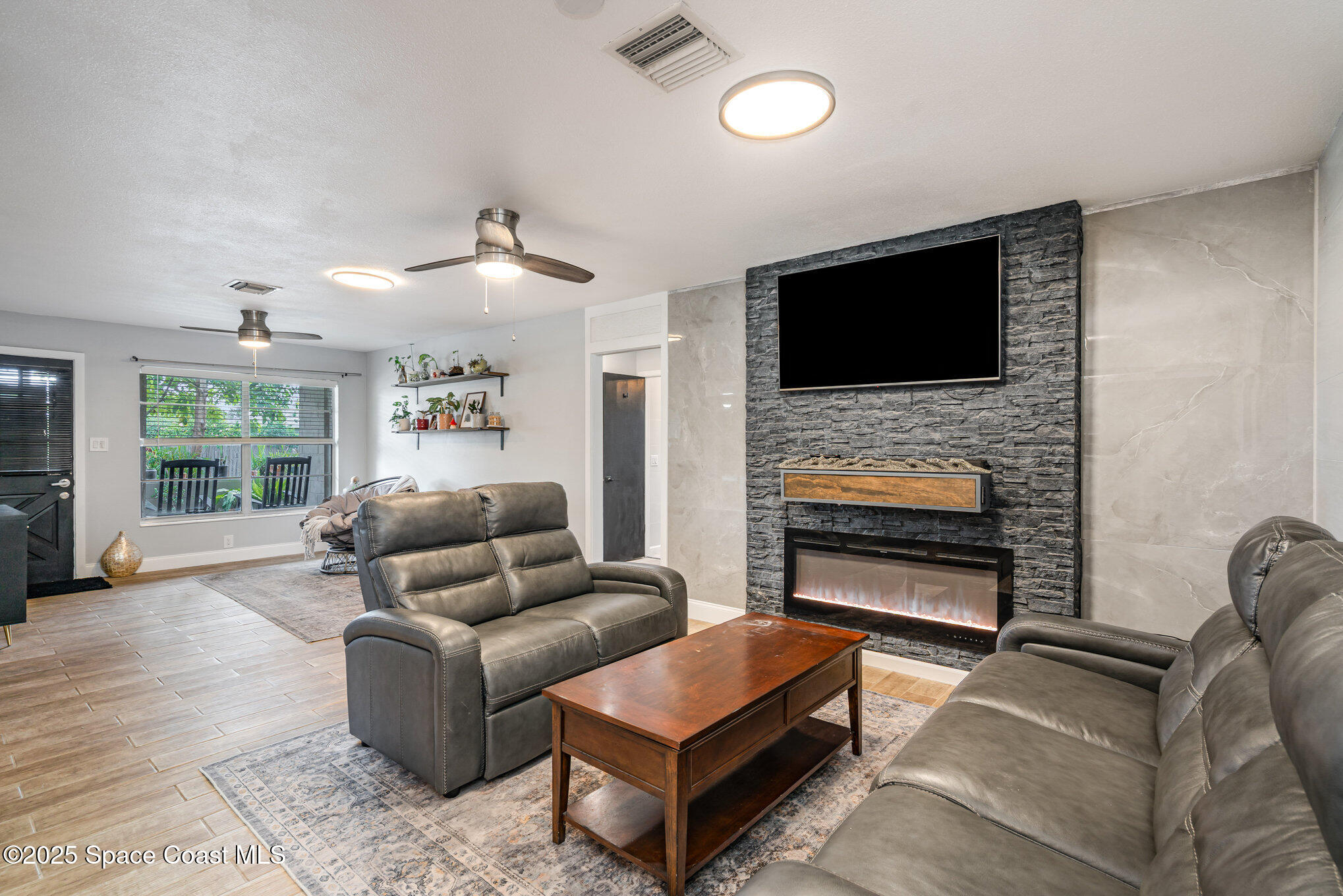 508 Comanche Avenue Melbourne, FL 32935 - Photo 7 of 21 a living room with furniture a flat screen tv and a fireplace