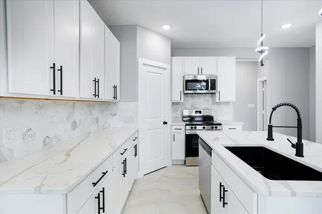 a kitchen with granite countertop a sink stove and cabinets