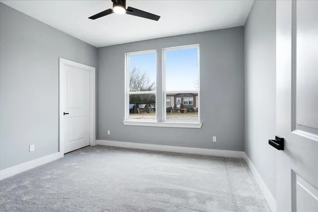 an empty room with windows and ceiling fan