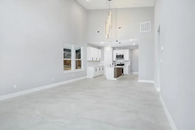 an empty room with kitchen and windows