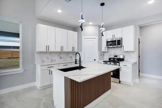a kitchen with kitchen island a sink stove and microwave