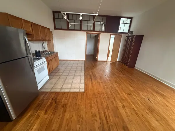 a kitchen with a refrigerator and wooden floor