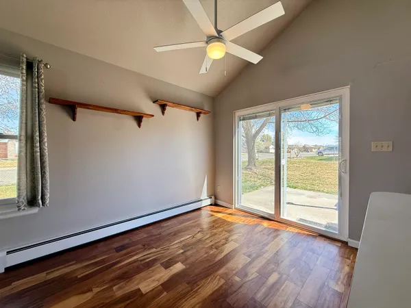 a view of an empty room with wooden floor and a window