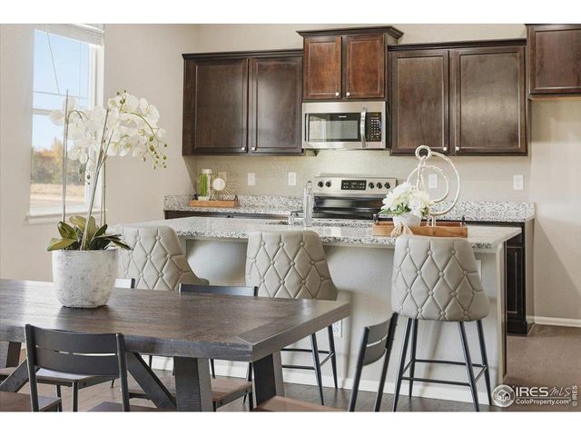 a kitchen with granite countertop a table chairs microwave and cabinets