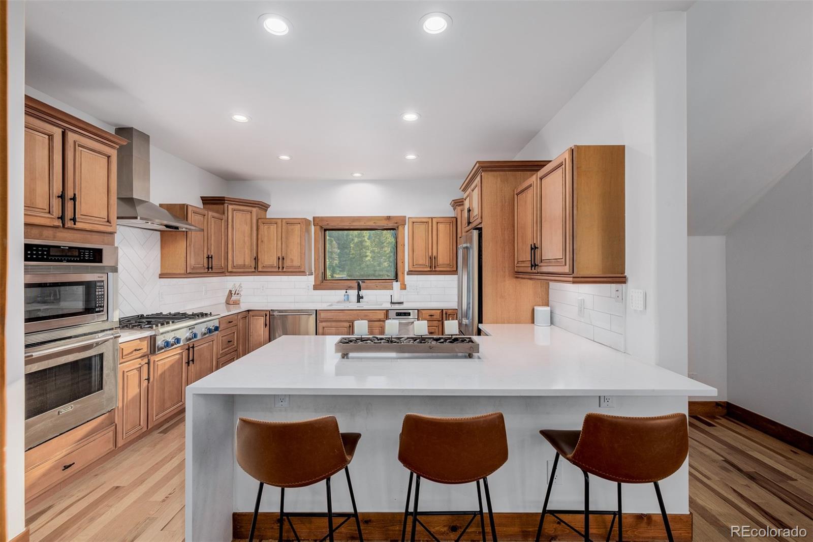 11272 Belle Meade Drive Conifer, CO 80433 - Photo 16 of 45 a kitchen with stainless steel appliances granite countertop a stove top oven a sink a dining table and chairs with wooden floor