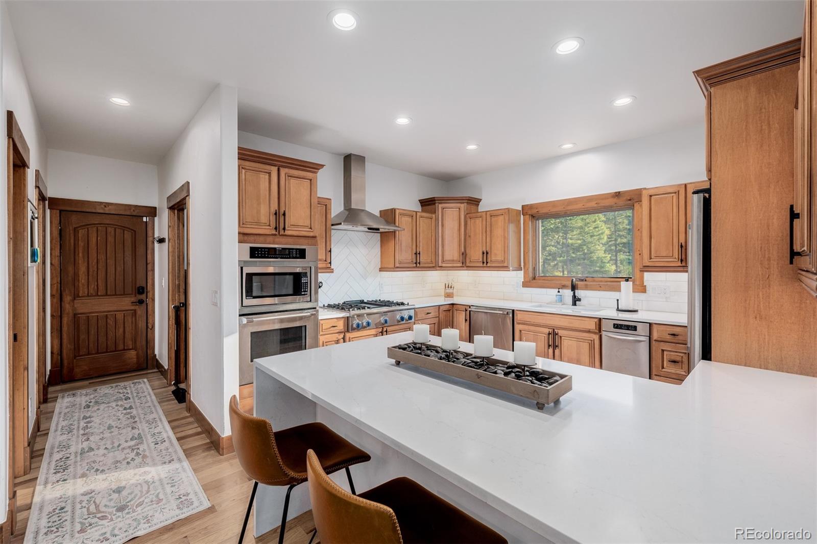 11272 Belle Meade Drive Conifer, CO 80433 - Photo 17 of 45 a kitchen with stainless steel appliances a stove a sink a refrigerator white cabinets and wooden floor