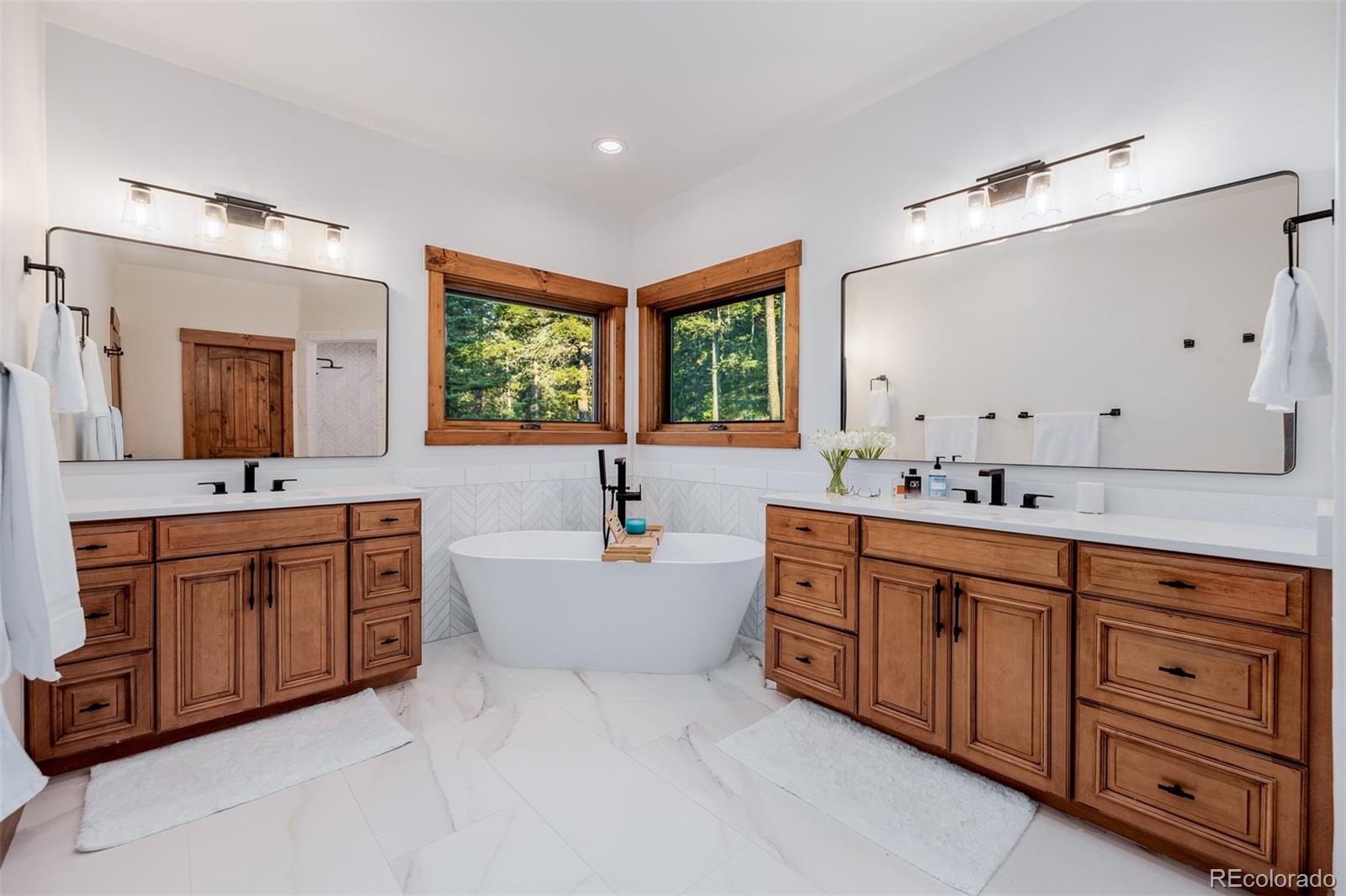 11272 Belle Meade Drive Conifer, CO 80433 - Photo 26 of 45 a spacious bathroom with double vanity a mirror a bathtub and a sink