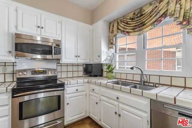 a kitchen with granite countertop a sink stainless steel appliances and cabinets