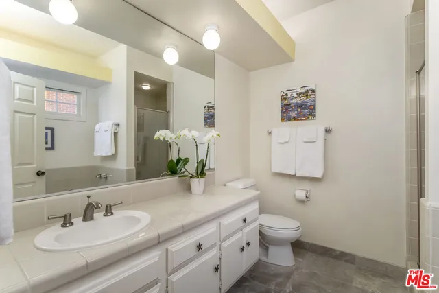 a bathroom with a granite countertop toilet a sink and a mirror