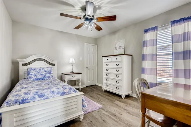 a bedroom with a bed a dresser and a chandelier