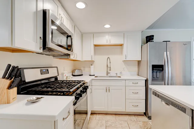 a kitchen with white cabinets and appliances
