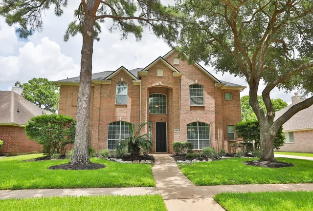 a front view of a house with a garden and trees