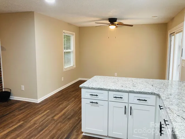 a hallway with granite countertop white cabinets and wooden floor