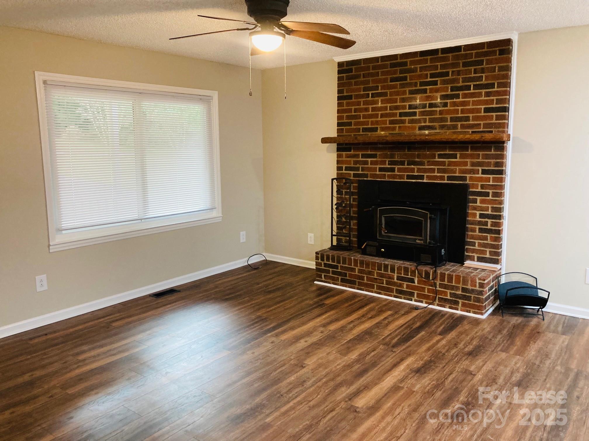 2177 Lynmore Drive Sherrills Ford, NC 28673 - Photo 7 of 18 an empty room with wooden floor a fireplace and windows