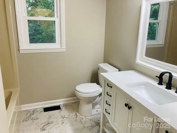 a bathroom with a sink a toilet and a window
