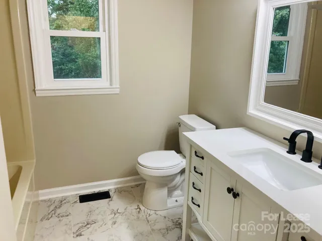 a bathroom with a sink a toilet and a window