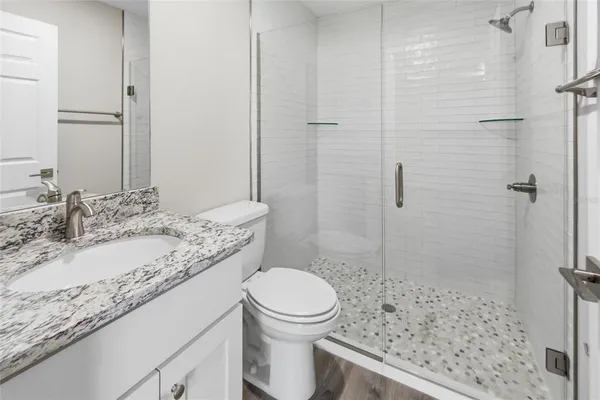 a bathroom with a granite countertop sink toilet and shower