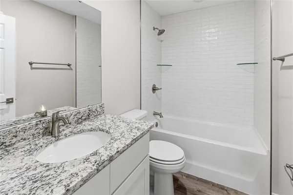 a bathroom with a granite countertop sink toilet and shower