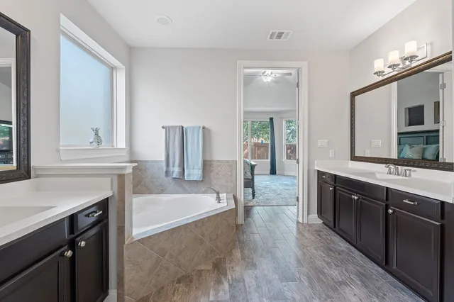 a spacious bathroom with a tub sink and mirror