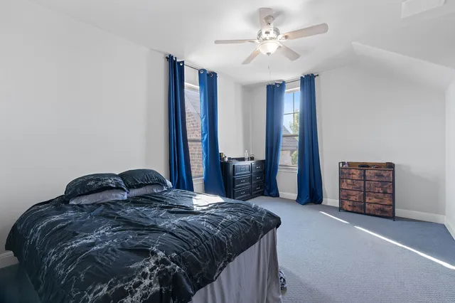 a bedroom with a bed a dresser and a chandelier