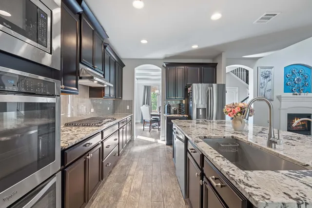 a kitchen with stainless steel appliances granite countertop a sink stove and refrigerator