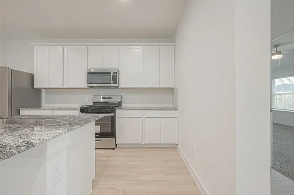 a kitchen with stainless steel appliances granite countertop a stove top oven a sink and white cabinets